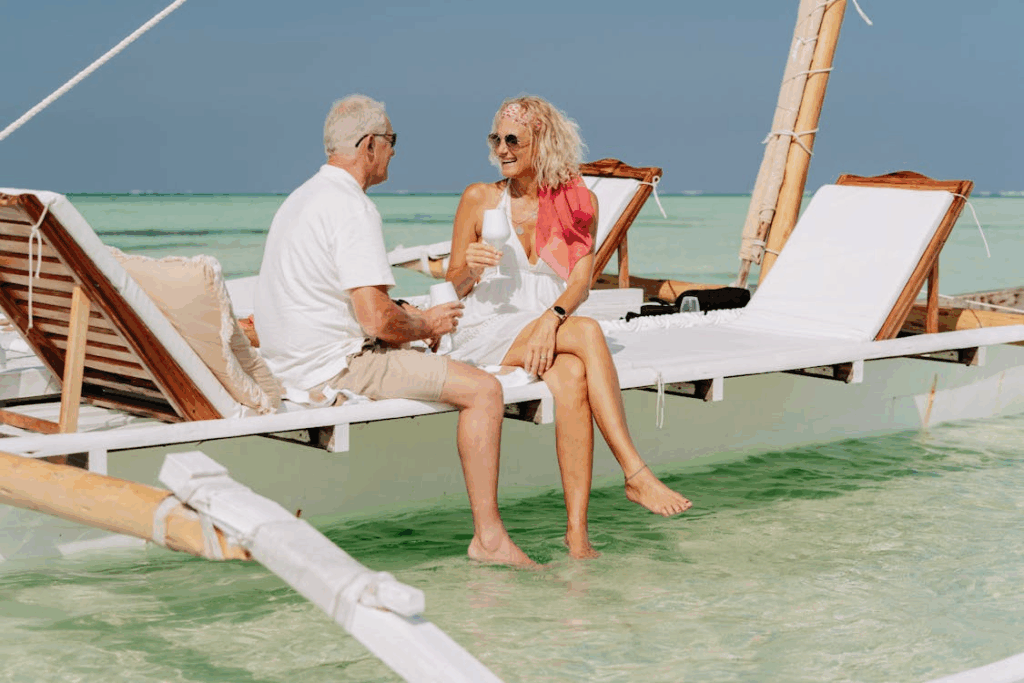 Happy retired couple relaxing on a beach lounge chair in the ocean, enjoying a bucket list vacation experience.