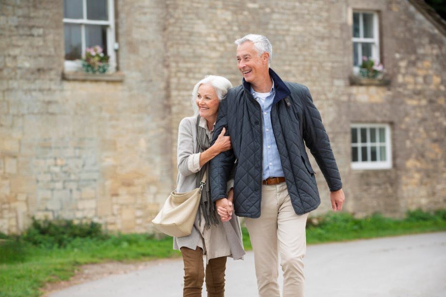 Happy retired couple walking together outside their home in retirement